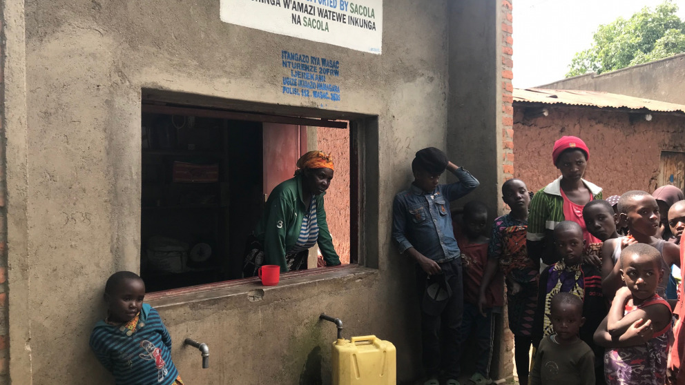 In Rwanda, a woman collects payments for water. The money is reinvested in the community. 